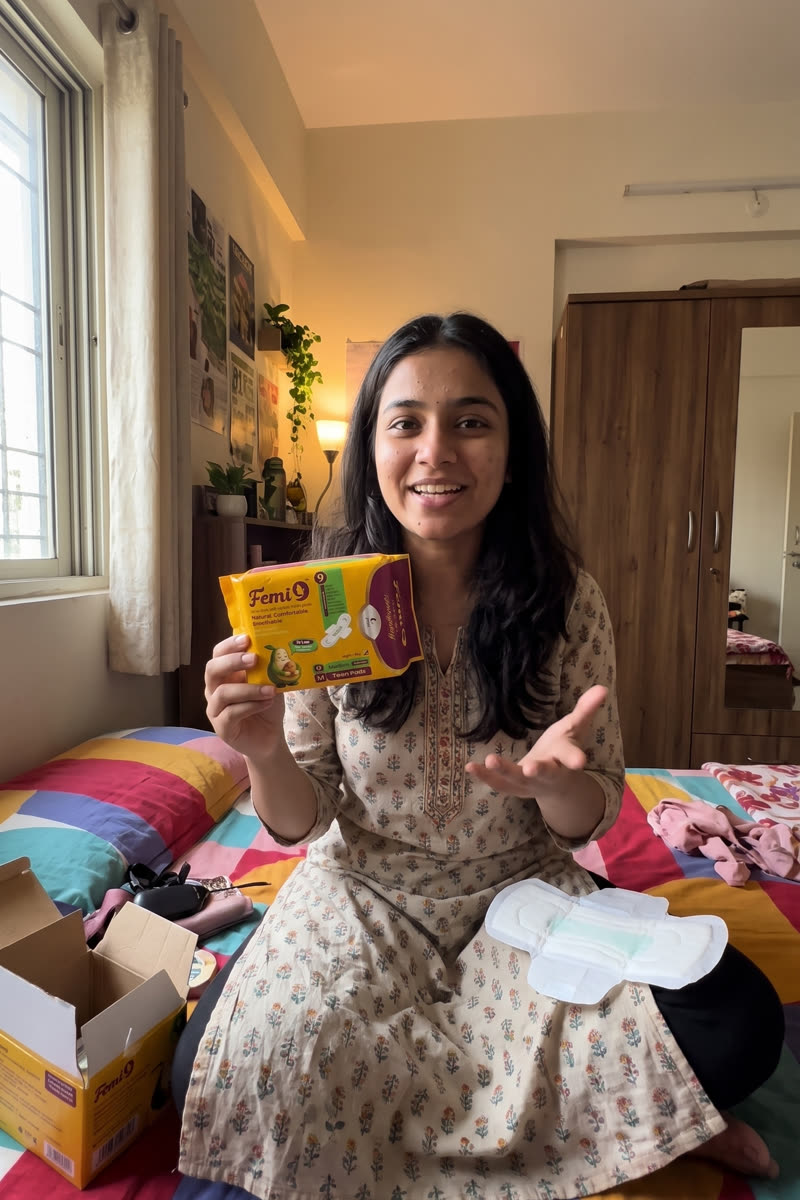 Woman in a bright bedroom holding a Femi9 245mm teen pads pack